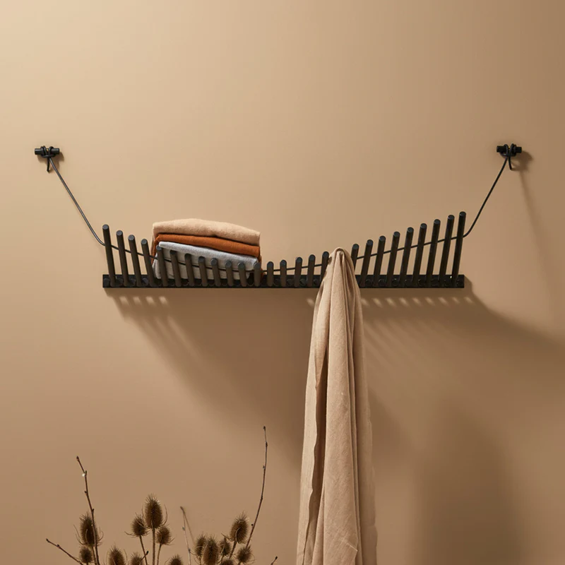 The Knaegt Coat Rack from Woud in black being used in a living room.