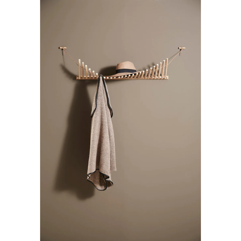 The Knaegt Coat Rack from Woud in white pigmented oak being used for clothes in a closet.