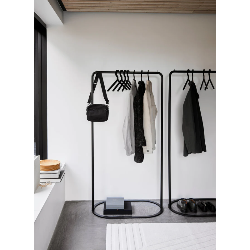 Two large O&O Clothes Racks being used in a hallway for guests to hang their coats, bags, and leave their shoes.