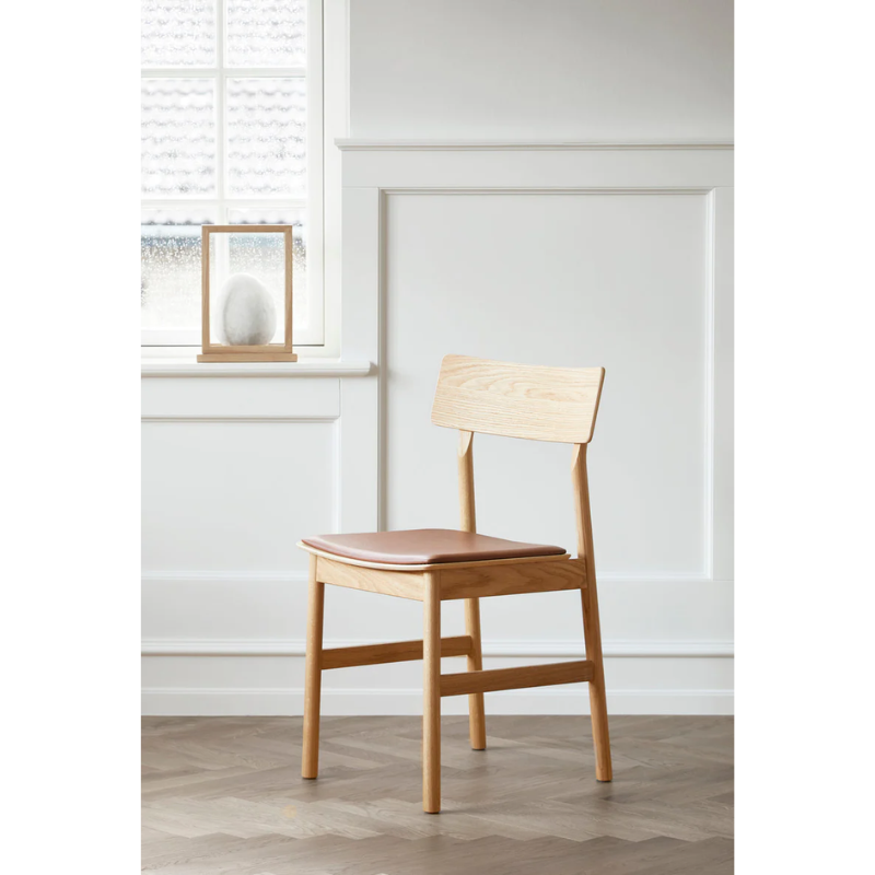 The Oiled Oak with Leather Pause Dining Chair 2.0 by Woud in a spacious area for a lifestyle shot.