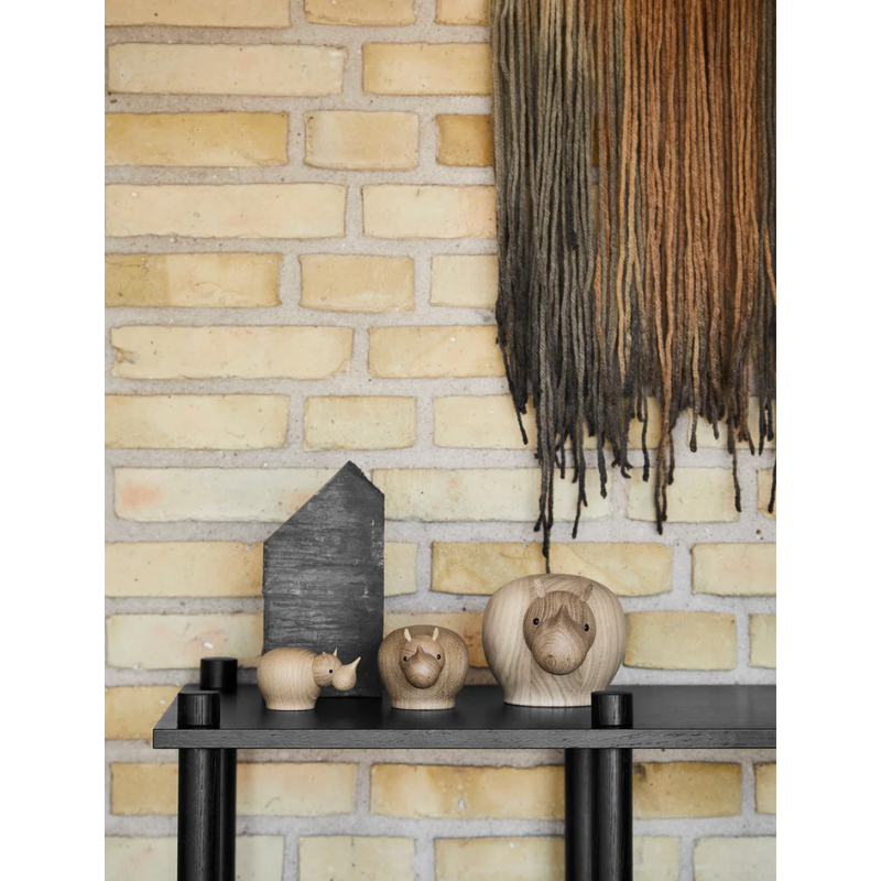 A lifestyle shot of the solid oak Rina Rhinoceros from Woud on top of a low table.