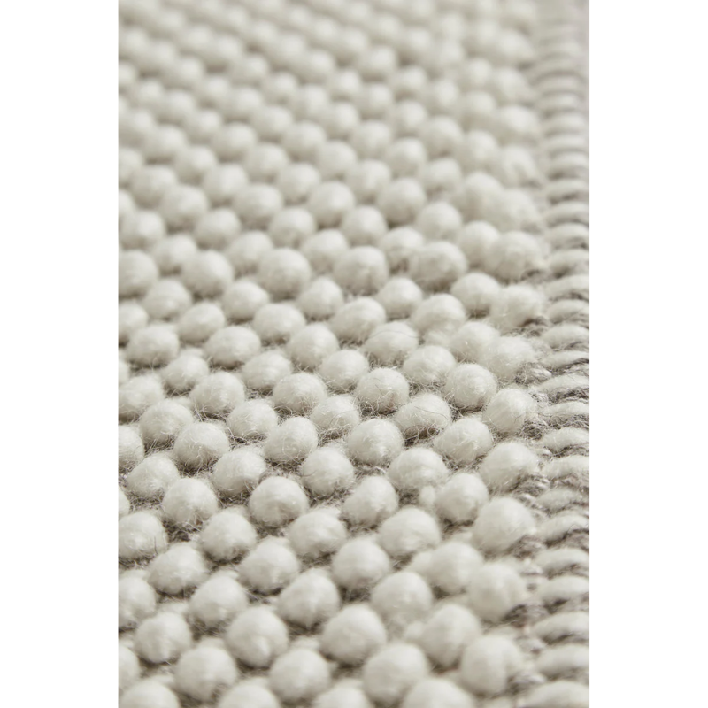 A close up on the fabric used for the Tact Rug from Woud in off white color.