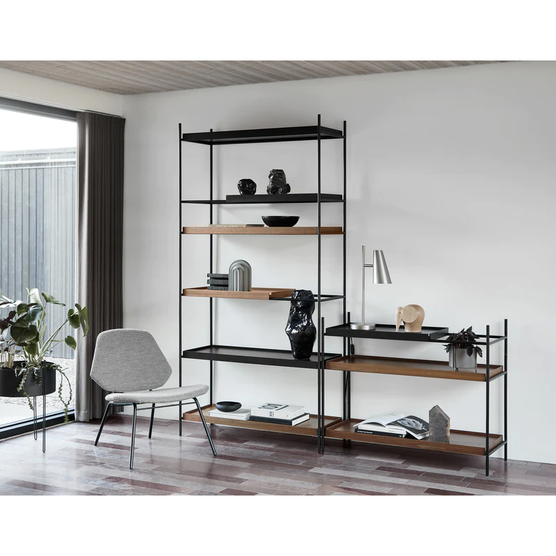 The Tray Shelf high and low from Woud in walnut being used within a living room with other Woud products decorating the shelves.