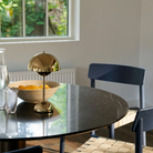 &Tradition VP9 Flowerpot Portable Table Lamp in brass plated on a dining room table.