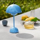 &Tradition VP9 Flowerpot Portable Table Lamp in Swim Blue being used on outdoor dining table.
