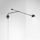 The antracite gray Ixa Arm Plug In Wall Sconce from Artemide in a living space.