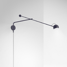 The blue Ixa Arm Plug In Wall Sconce from Artemide in a family area.
