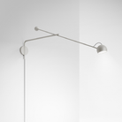 The white Ixa Arm Plug In Wall Sconce from Artemide in a home office.