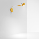 The yellow Ixa Reading Wall Sconce from Artemide in a home office.