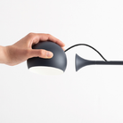 The anthracite gray Ixa Table Lamp from Artemide in a home office, highlighting the removable light.