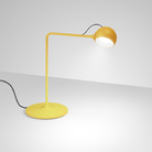 The yellow Ixa Table Lamp from Artemide in a living area.