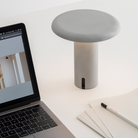 The Takku Portable Lamp from Artemide in white in an office.