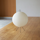 The Mari Lamp - A122 from Asano, a small rice paper table lamp turned off on the floor of a living room.