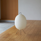 The Tawara A121 by Asano is a small floor lamp made of rice paper. Image of lamp turned off on the floor.