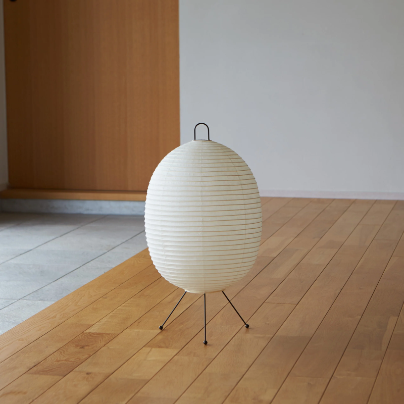 The Tawara A121 by Asano is a small floor lamp made of rice paper. Image of lamp turned off on the floor.