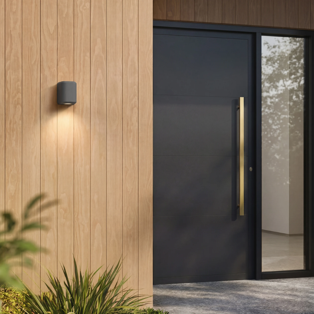 The Brixham Wall Single outdoor sconce in charcoal concrete by Astro Lighting installed by a front door during the day.