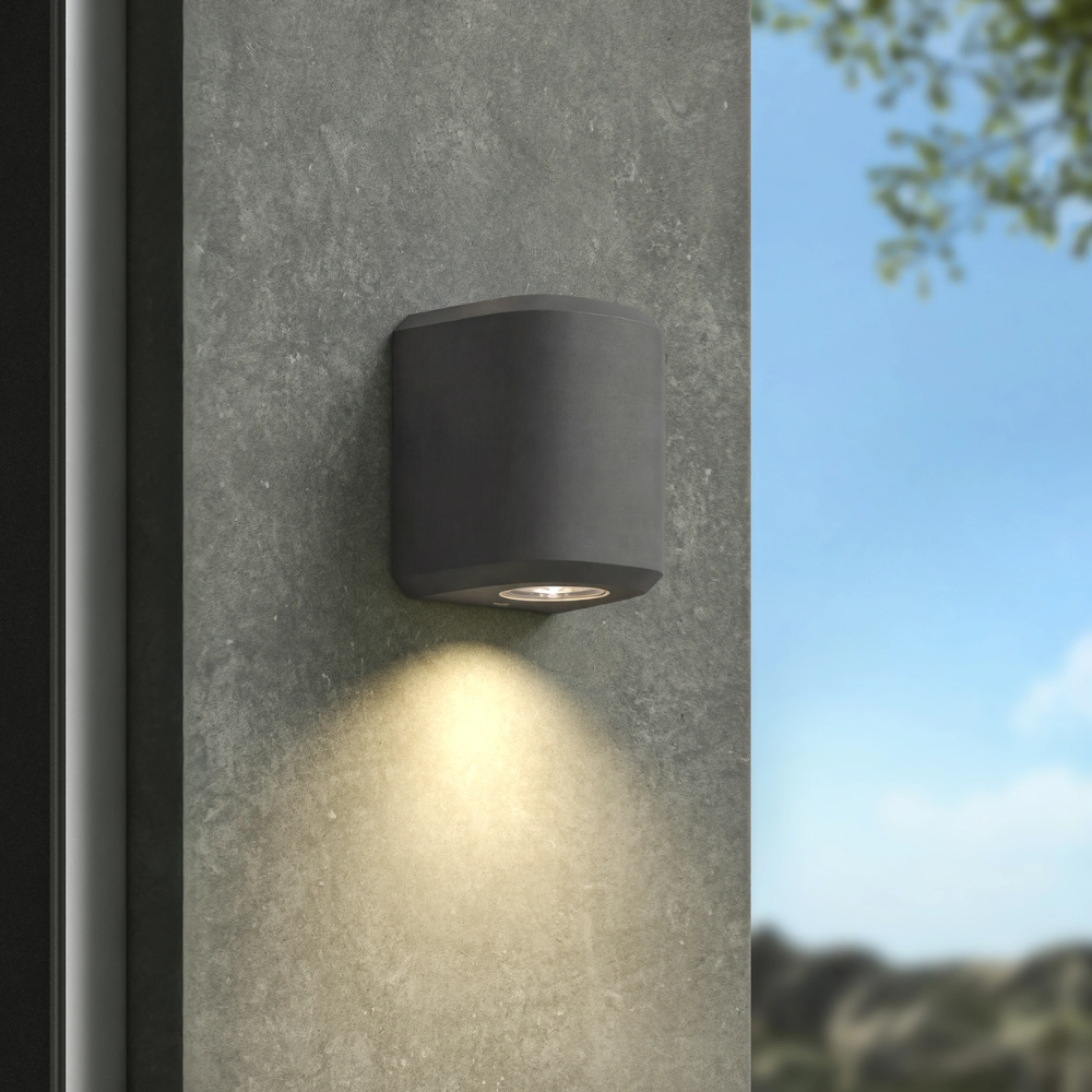 The Brixham Wall Single outdoor sconce in charcoal concrete by Astro Lighting installed on a concrete wall during the day.