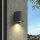 The Brixham Wall Single outdoor sconce in charcoal concrete by Astro Lighting installed on a concrete wall during the day.