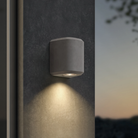 The Brixham Wall Single outdoor sconce in grey concrete by Astro Lighting installed on a concrete wall at night.