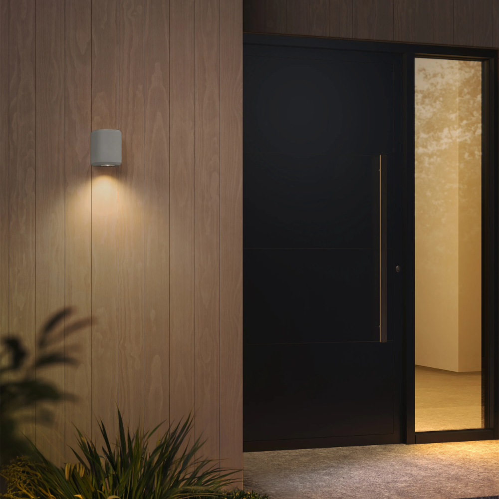 The Brixham Wall Single outdoor sconce in grey concrete by Astro Lighting installed by a front door at night.