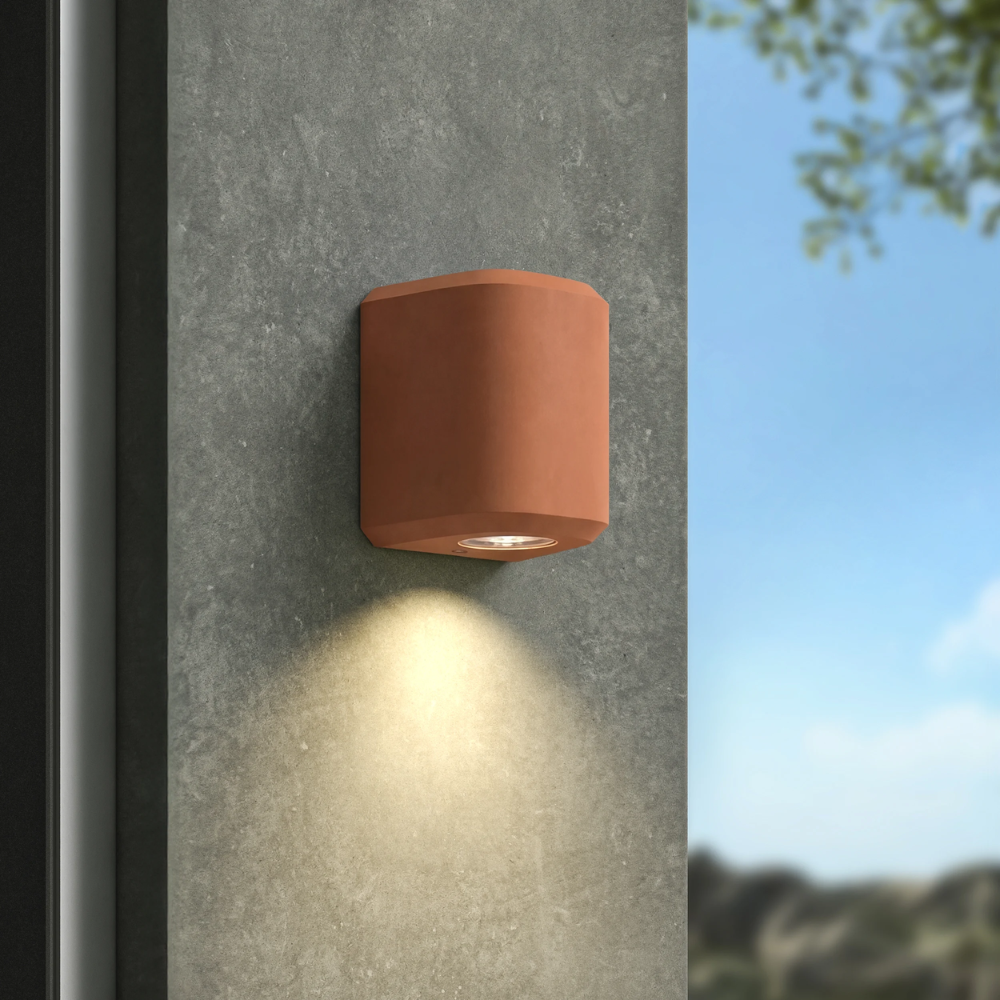 The Brixham Wall Single outdoor sconce in terracotta concrete by Astro Lighting installed on a concrete wall during the day.