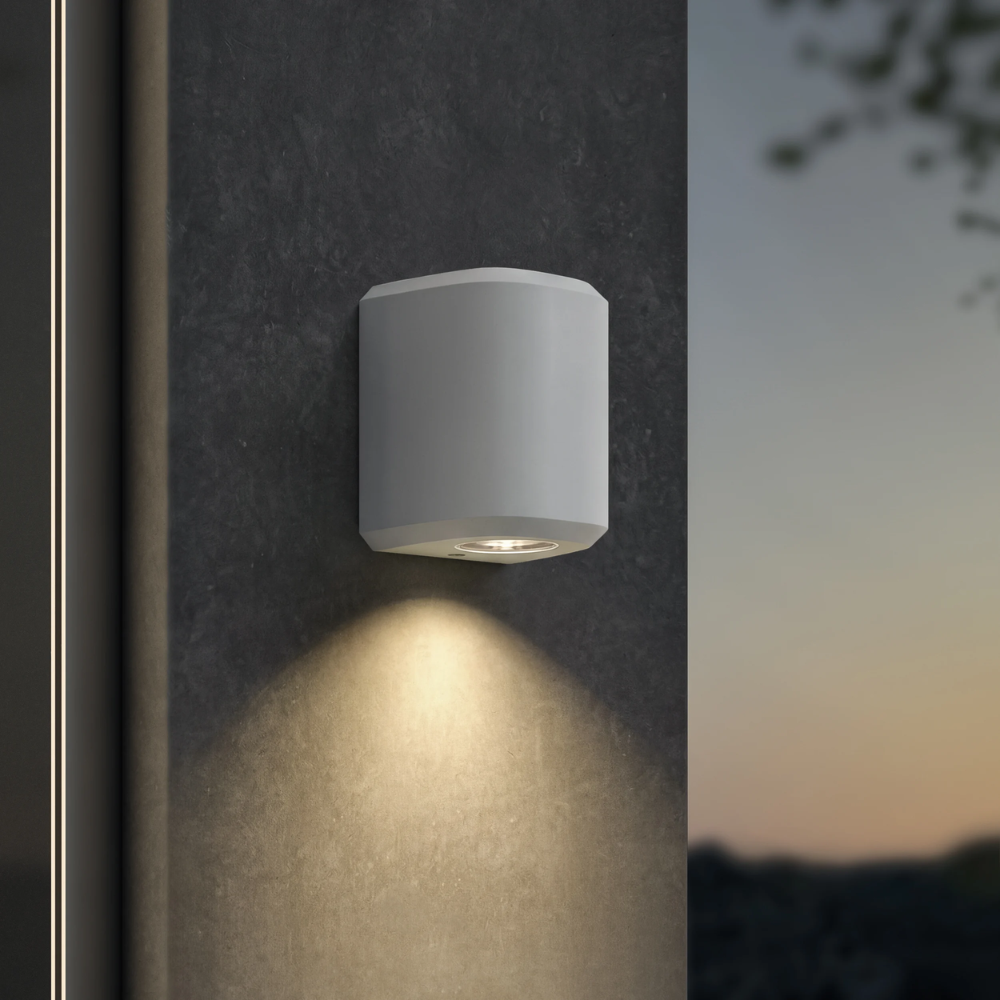 The Brixham Wall Single outdoor sconce in white concrete by Astro Lighting installed outside at night.