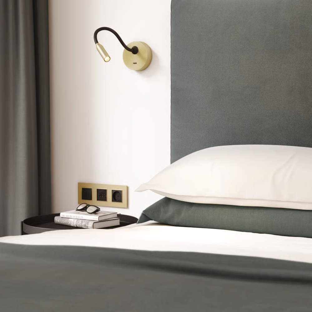 The matte gold Lucca Surface Wall Sconce from Astro Lighting in a hotel bedroom.