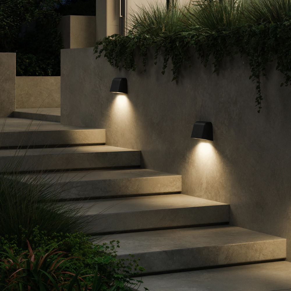 The Mast Twin Coastal Outdoor Wall Sconce by Astro Lighting in charcoal concrete installed outside on a wall in a stairway at night.