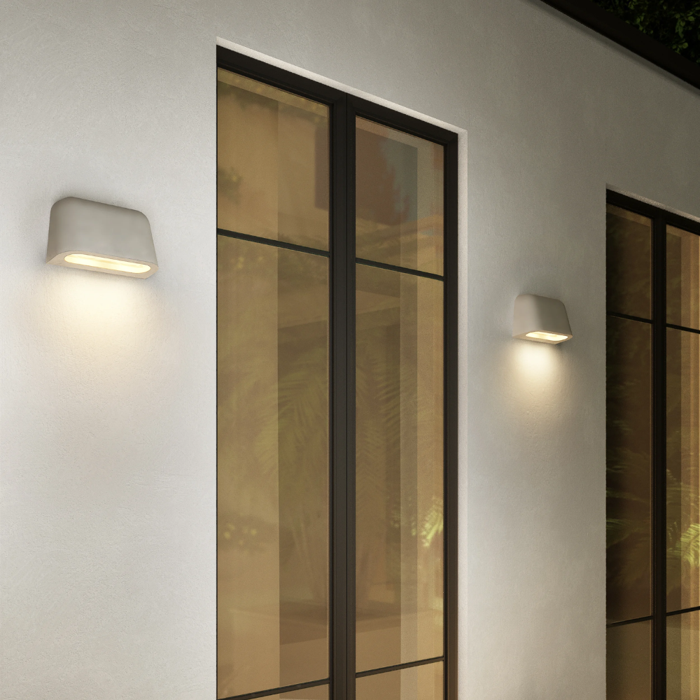 The Mast Twin Coastal Outdoor Wall Sconce by Astro Lighting in grey concrete installed on the exterior of a home at night.
