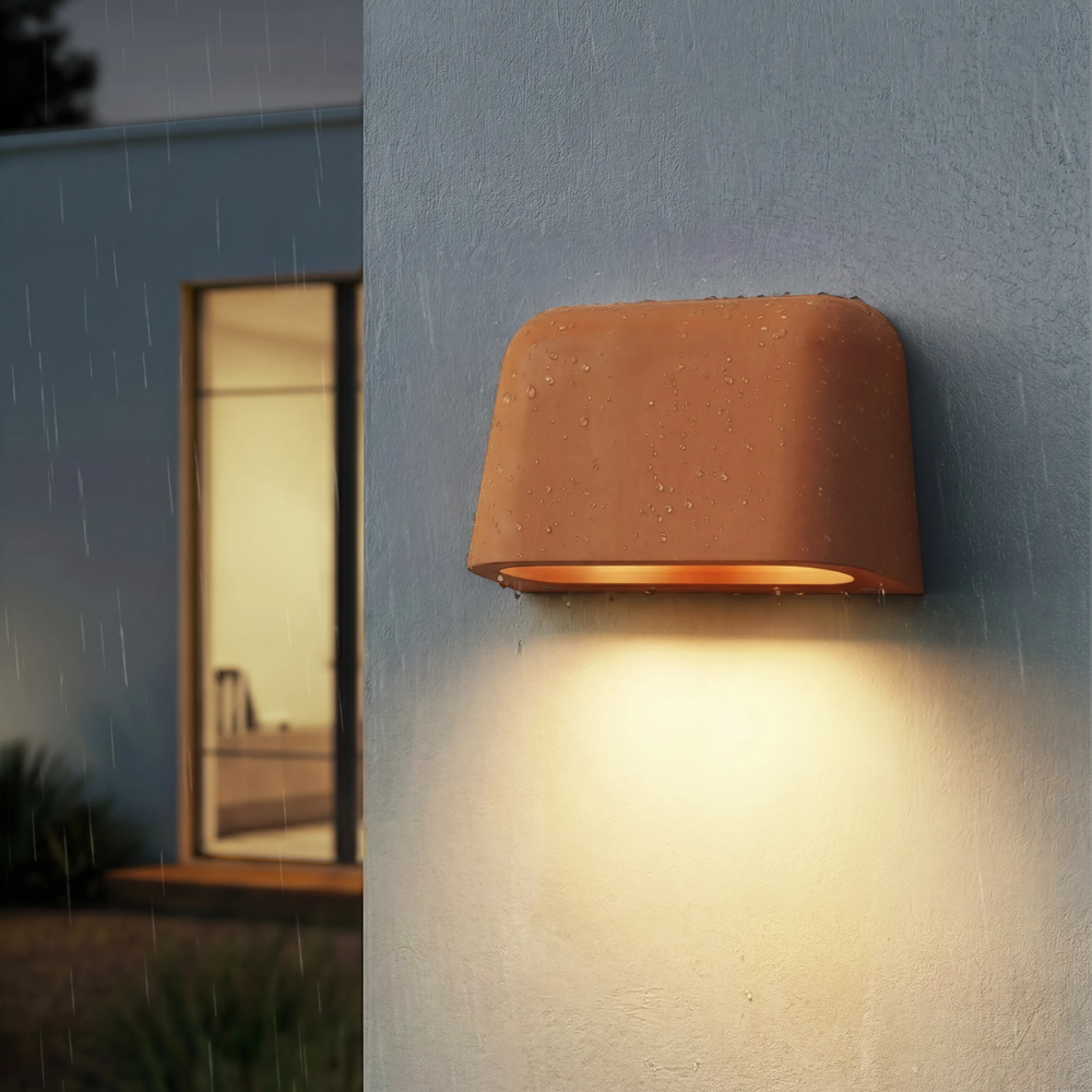 The Mast Twin Coastal Outdoor Wall Sconce by Astro Lighting in terracotta concrete installed outside at night.