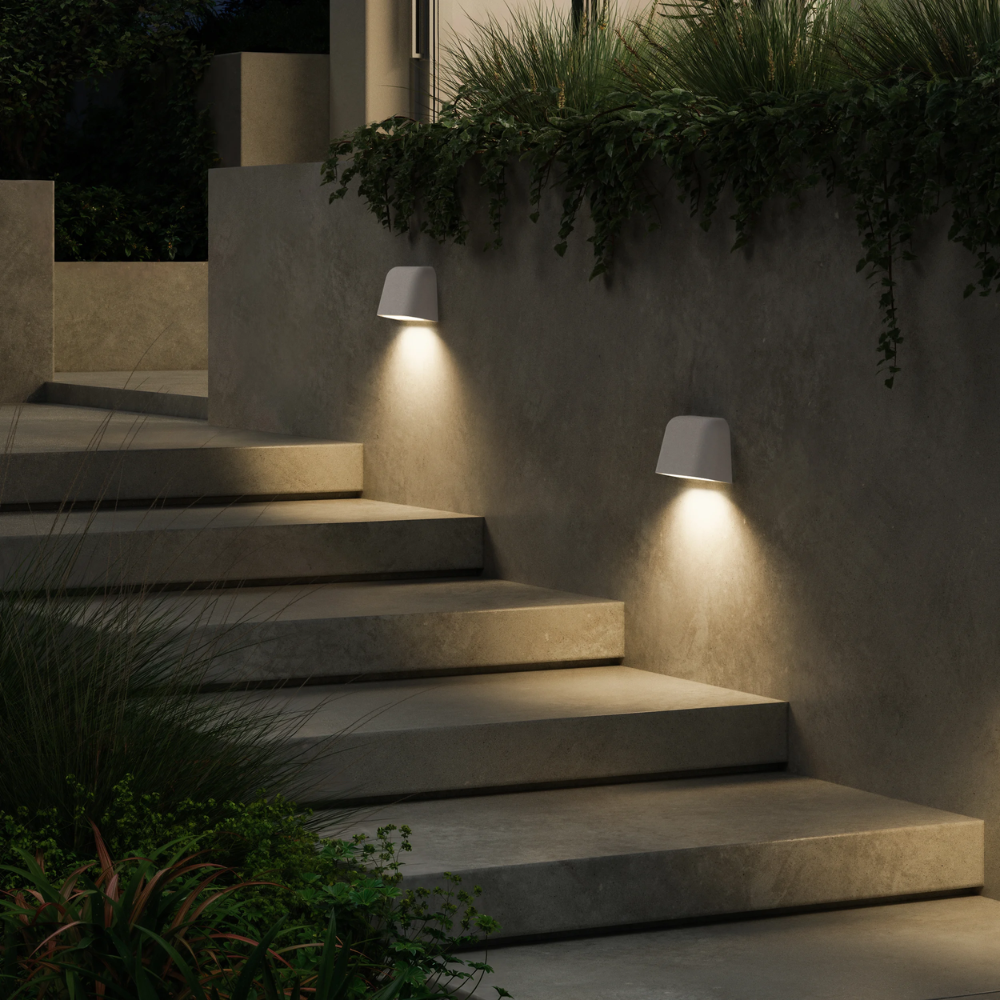 The Mast Twin Coastal Outdoor Wall Sconce by Astro Lighting in white concrete installed on a walkway at night.