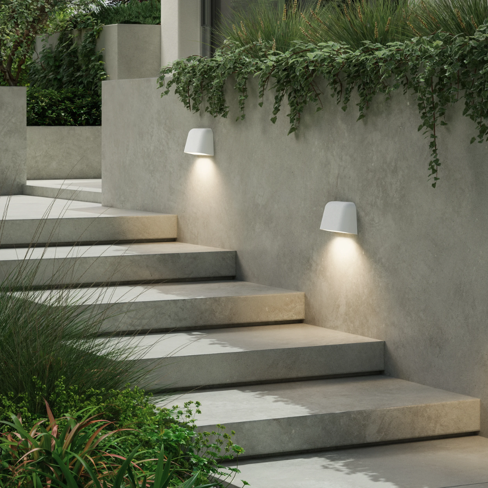 The Mast Twin Coastal Outdoor Wall Sconce by Astro Lighting in white concrete installed in a walkway at dusk.