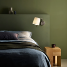 The matte nickel Mitsu Swing Arm Wall Sconce from Astro Lighting with the white shade in a primary bedroom.