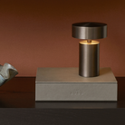 The Column Portable Table Lamp from Audo Copenhagen in anodized aluminum in a bedroom.