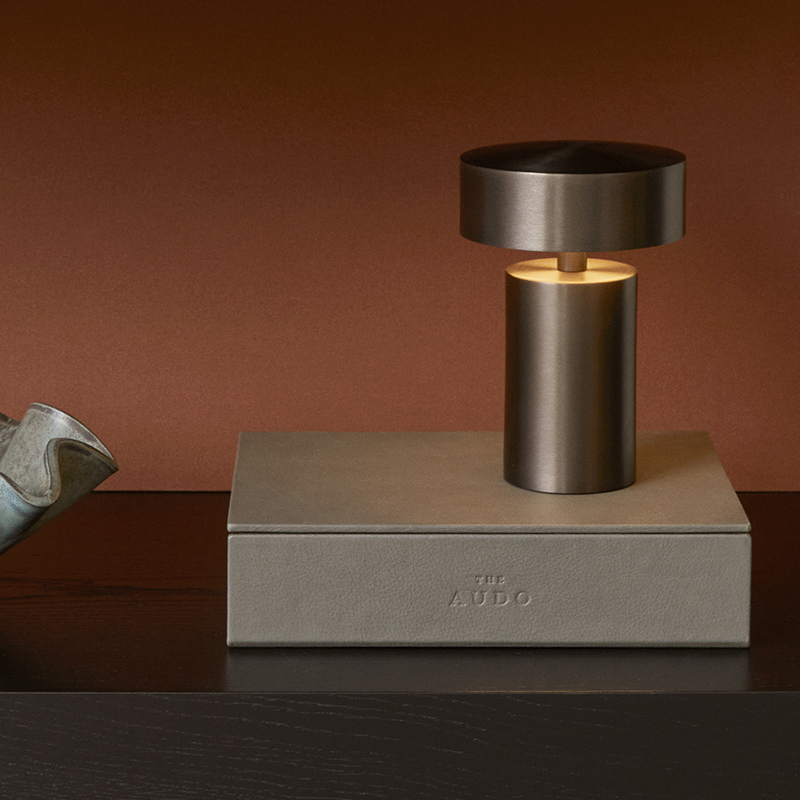 The Column Portable Table Lamp from Audo Copenhagen in anodized aluminum in a bedroom.