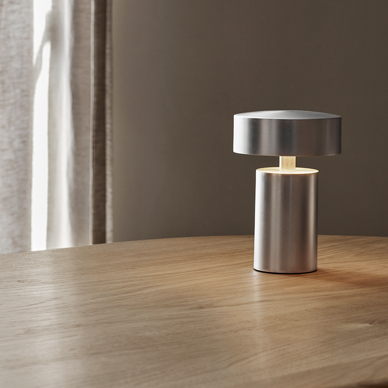 The Column Portable Table Lamp from Audo Copenhagen in brushed aluminum in a dining room.