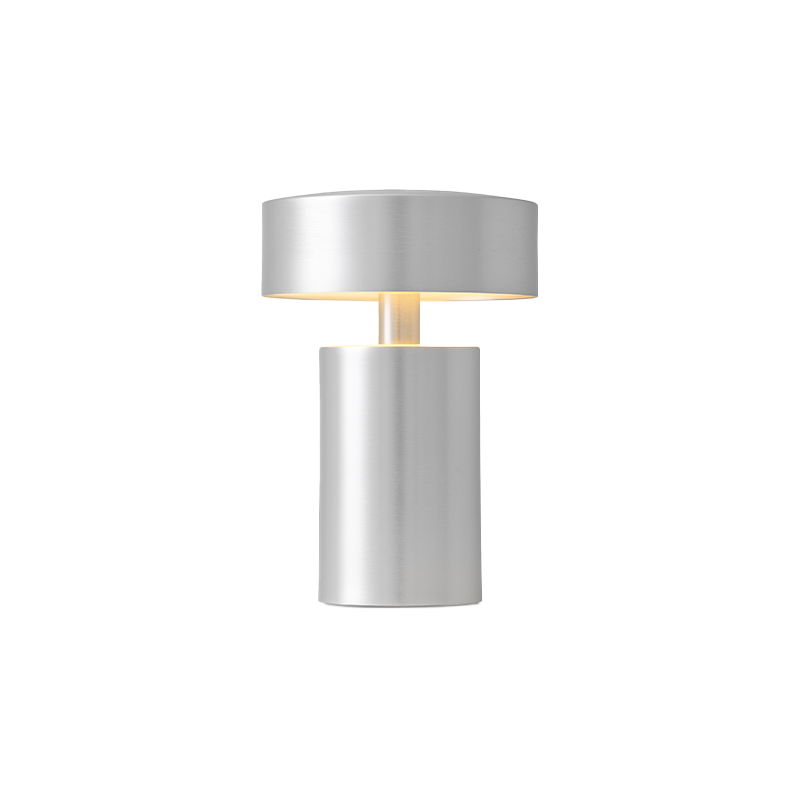 The Column Portable Table Lamp from Audo Copenhagen in brushed aluminum with the light on.