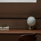 The JWDA Portable Table Lamp from Audo Copenhagen in alabaster white in a home office.