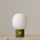 The JWDA Portable Table Lamp from Audo Copenhagen in dusty green in a entryway.