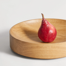 The Cusp Small Bowl from Blu Dot in white oak in a living room.