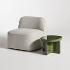 The olive Small Talk Short Side Table from Bludot with looksee swivel lounge chair in studio.
