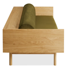 The Souvenir Sofa from Blu Dot with the loden green velvet upholstery and white oak frame from the side at an angle.