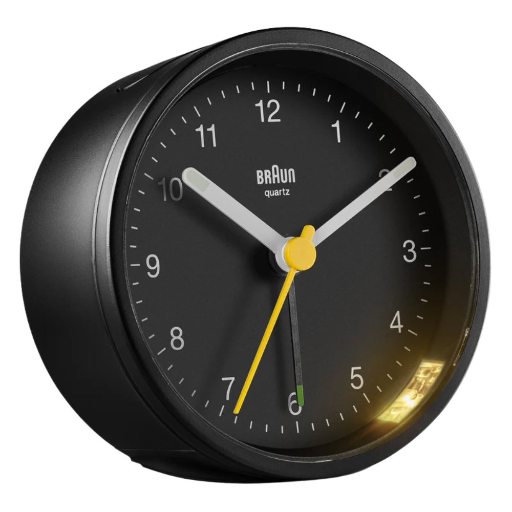 The black BC12 Round Alarm Clock by Braun from a side angle.