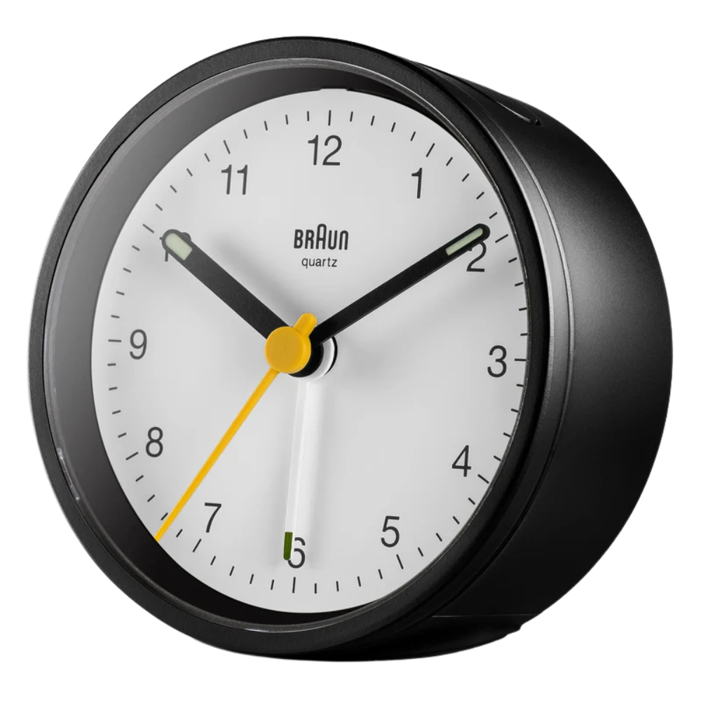 The black and white BC12 Round Alarm Clock by Braun from a side angle.
