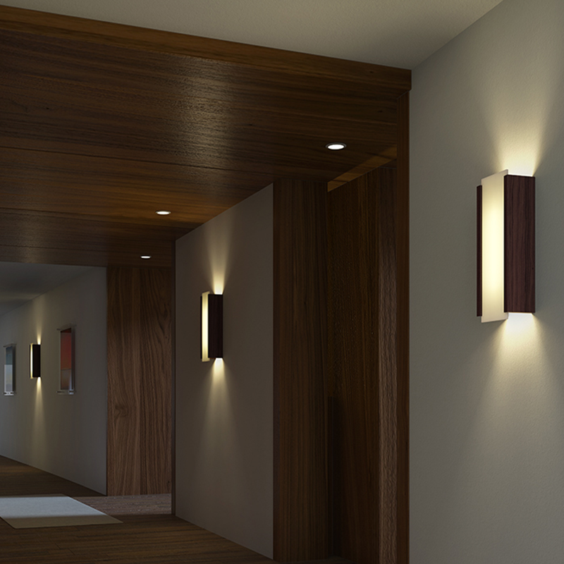 The Capio Sconce from Cerno in dark stained walnut in a hotel hallway.