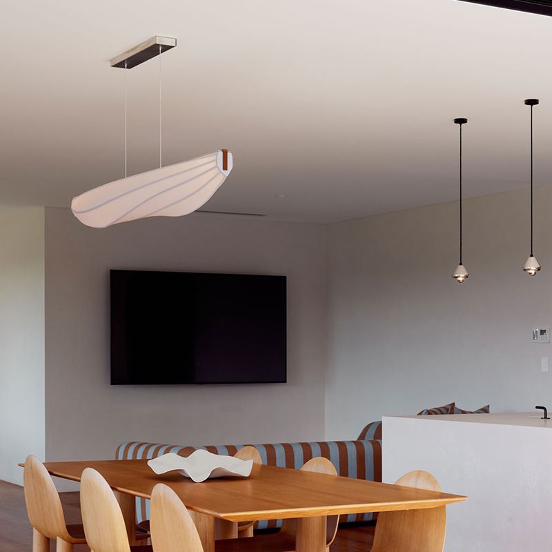 The Lenis Linear Pendant from Cerno in walnut in a living room.