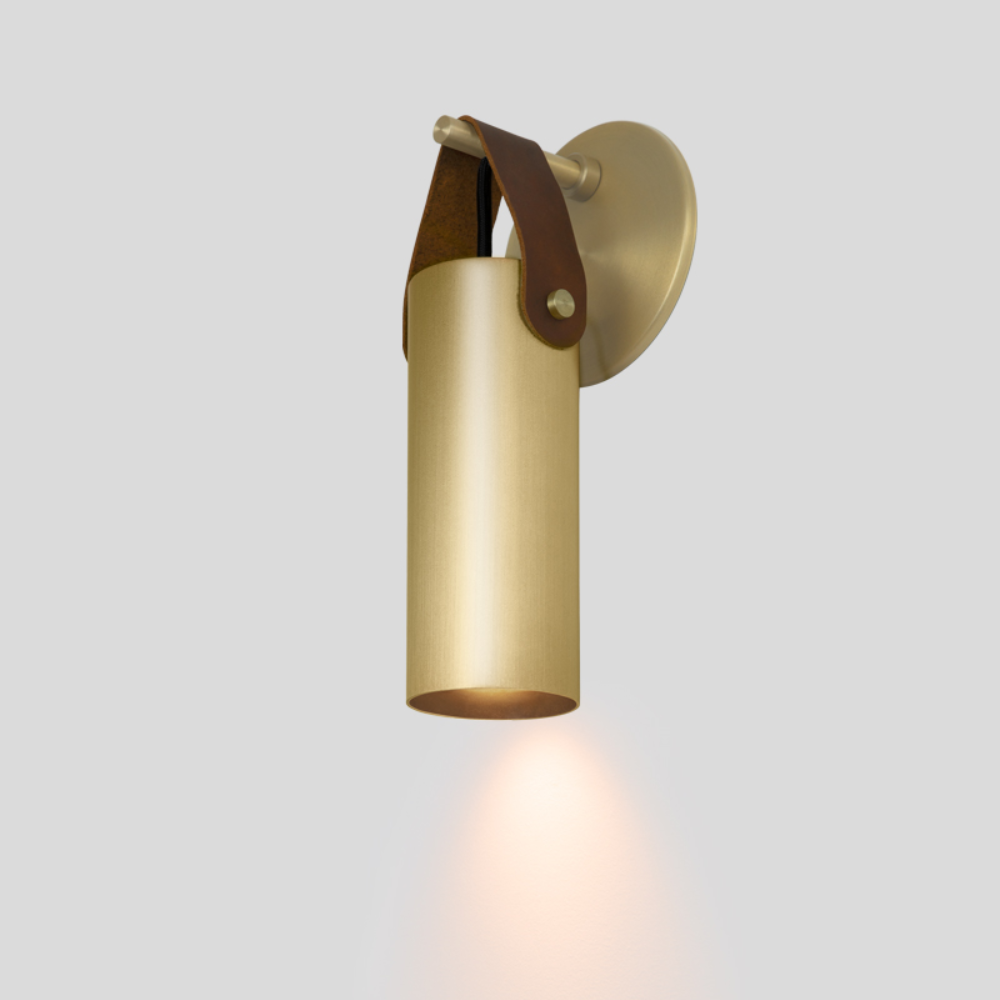 The brass and brown Spero Wall Sconce from Cerno in a studio.