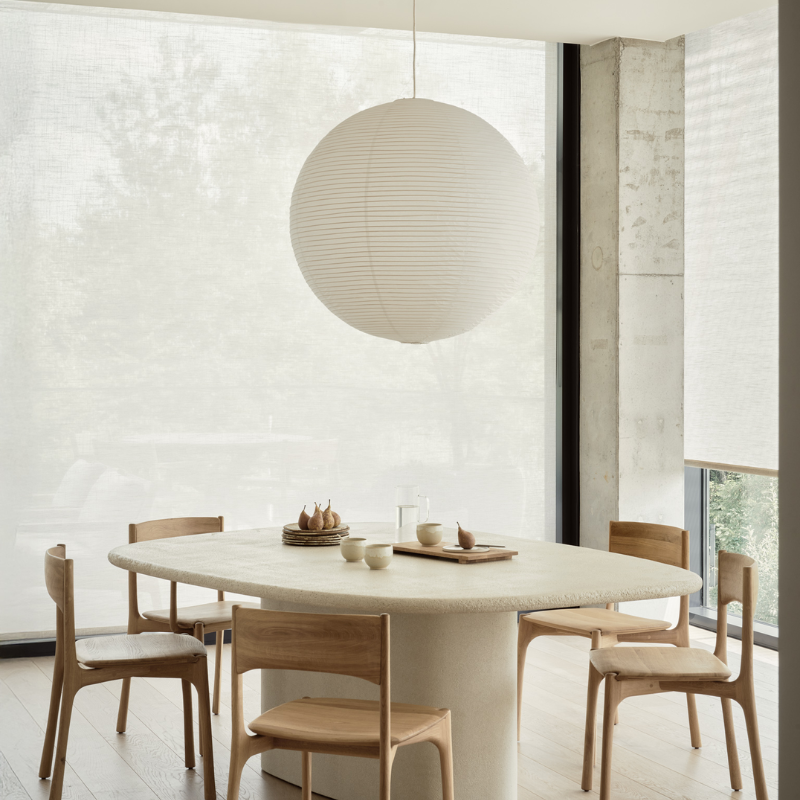 The Elements Pebble Dining Table by Ethnicraft in a modern and minimalistic dining room with chairs.