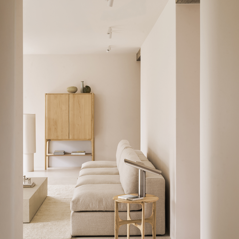 The Oak PI Cupboard by Ethnicraft in a modern living room with a beige sofa and side table.