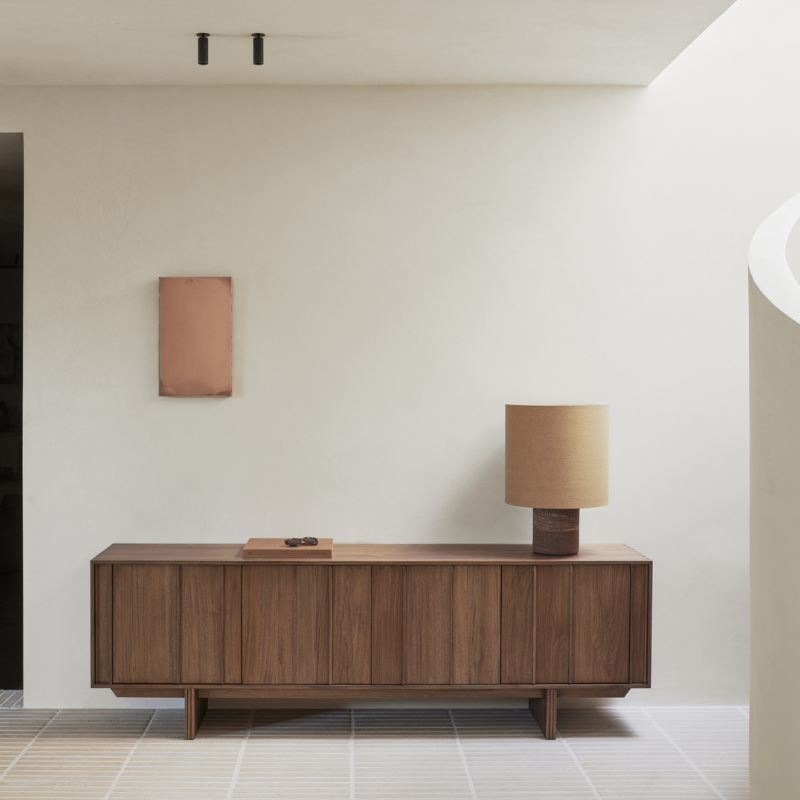 The Pillar Sideboard by Ethnicraft with a lamp on top against a white wall in the living room. all-groups